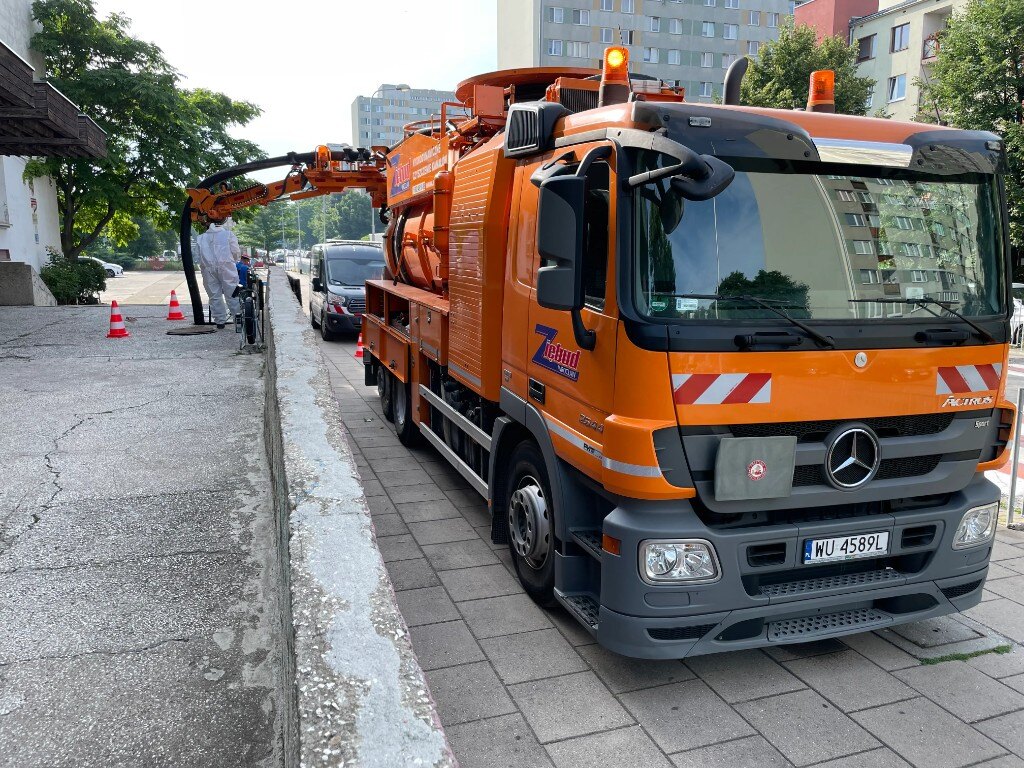 Pomarańczowy wóz ciśnieniowo-ssący ZIĘBUD podczas czyszczenia kanalizacji we Wrocławiu