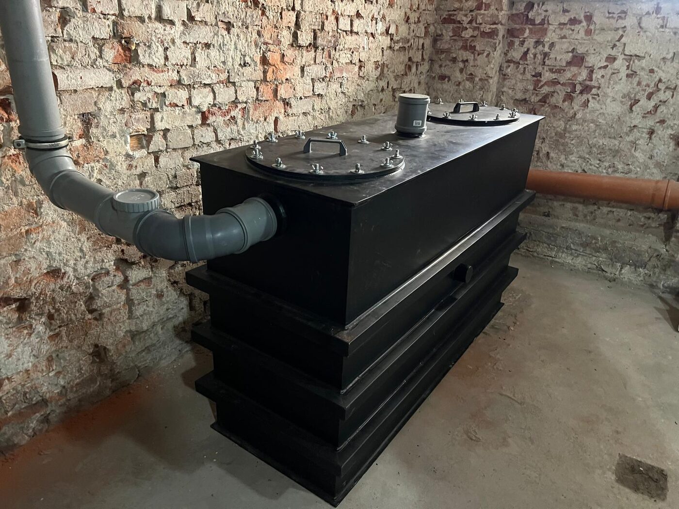 Separator tłuszczu zamontowany w piwnicy budynku, podłączony rurami do instalacji kanalizacyjnej